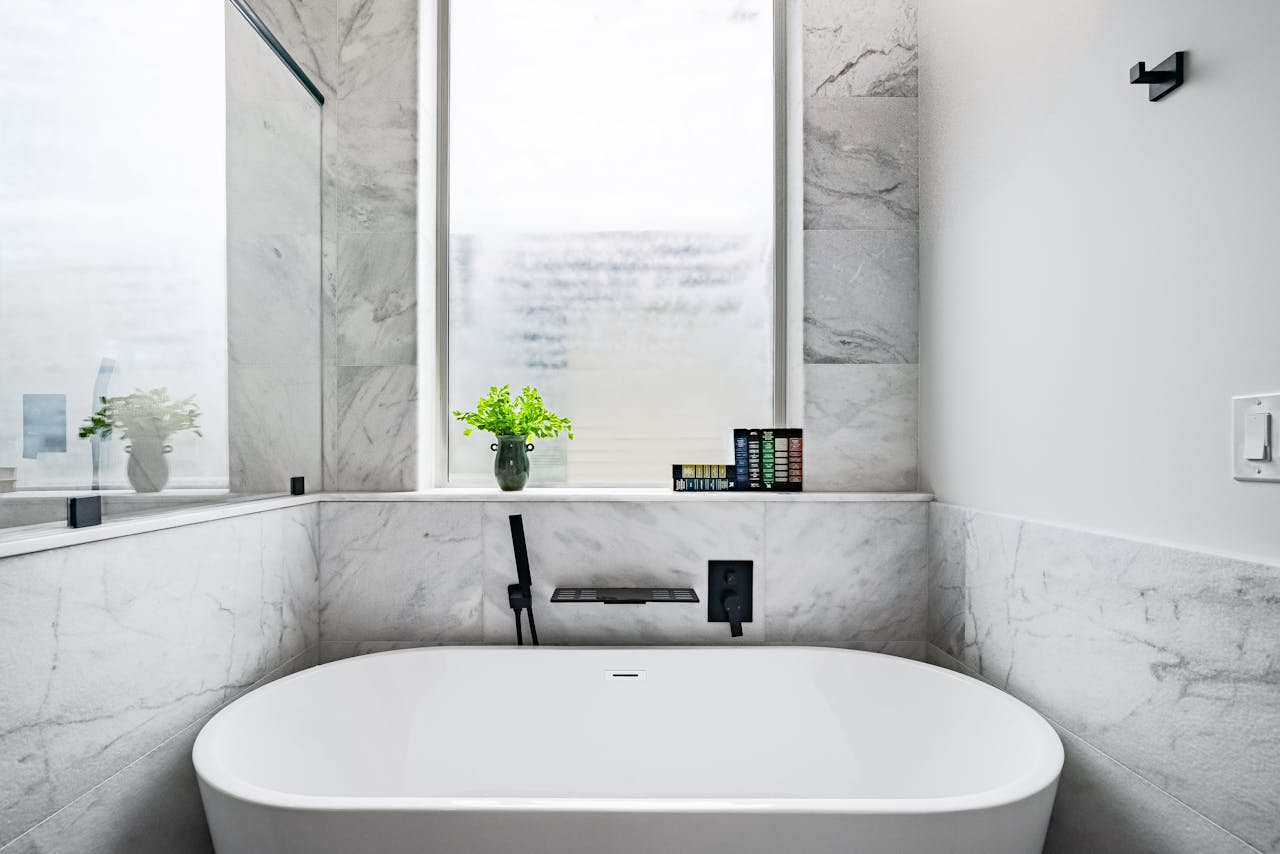 mission-02 Luxurious marble bathroom featuring a stylish white bathtub and minimalist decor.