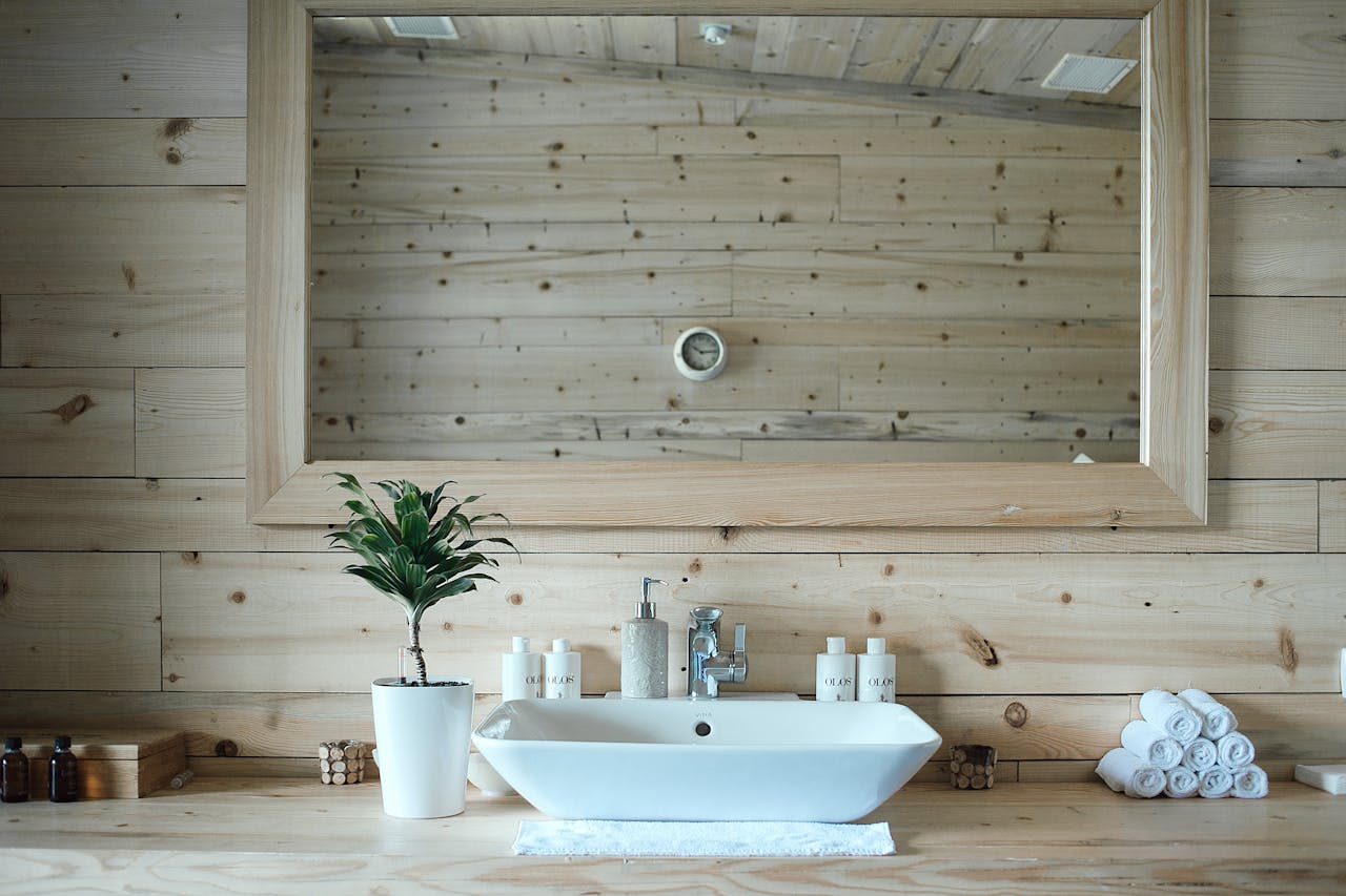 our-story-01 Stylish interior design of contemporary bathroom with wooden walls and big mirror above sink and table with toiletries